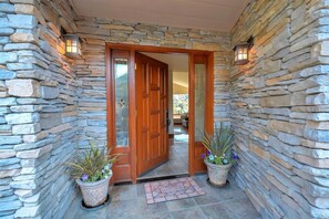 A stone-walled entrance with a wooden door, potted plants, and a welcome mat. - Farpoint: Heated Infinity Pool, Mountain Views (Santa Rosa)