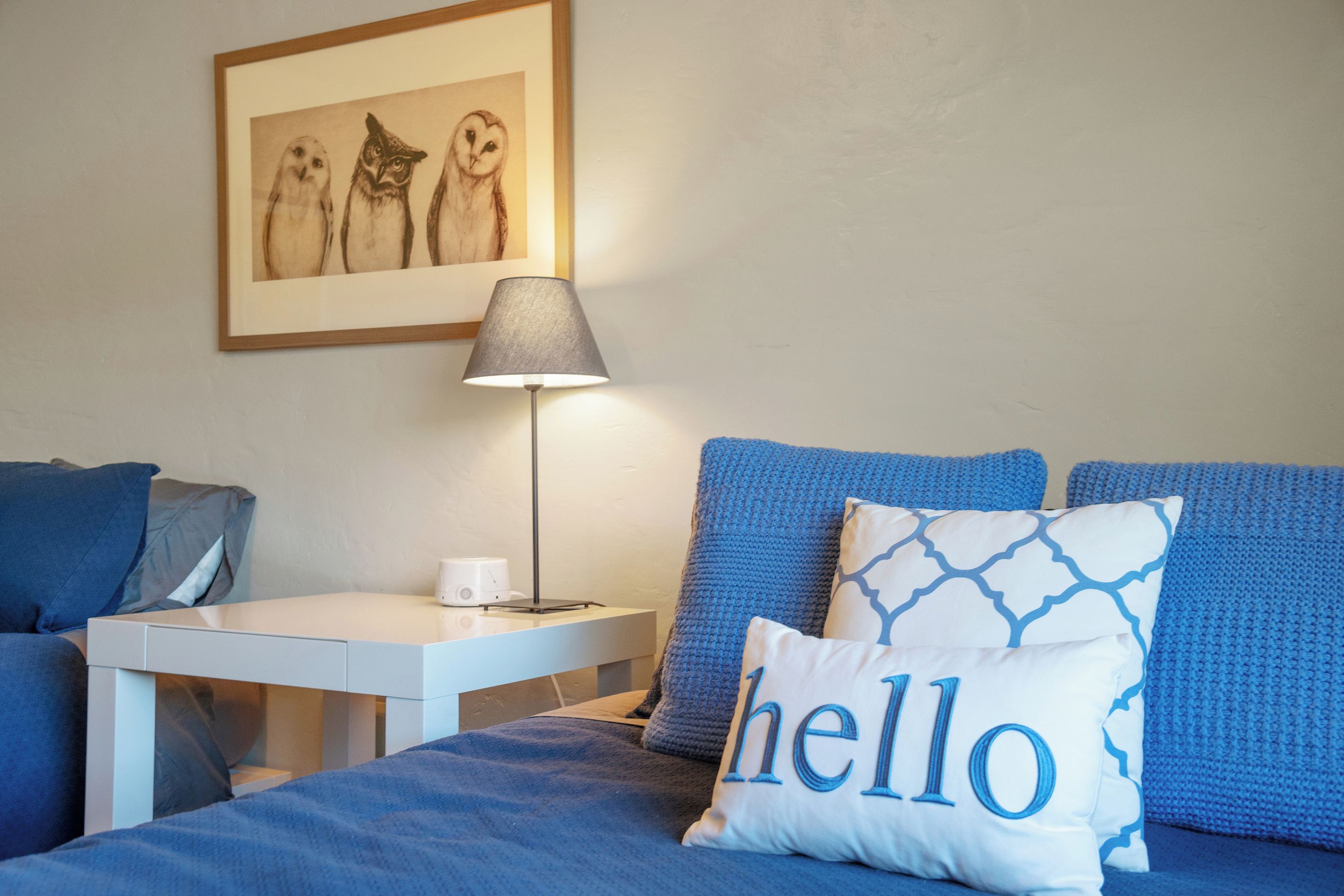 A bedroom with a bed, a nightstand, a lamp, and a framed picture on the wall.