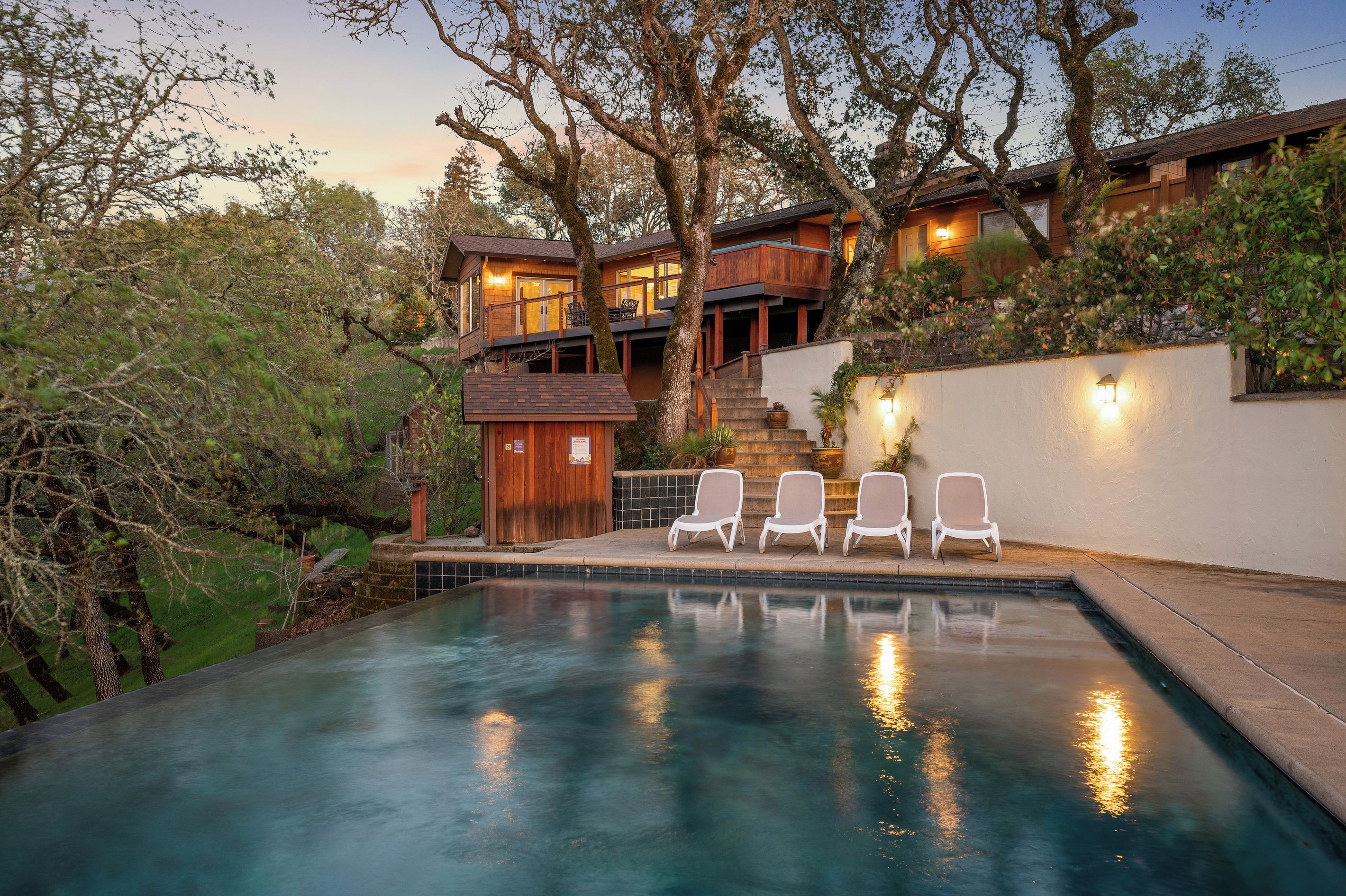 A two-story house with a swimming pool, outdoor seating, and a staircase leading to the upper level.