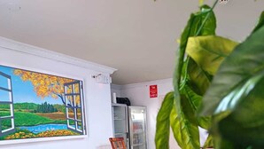Uma sala de estar com sofá, poltrona, quadro e geladeira.