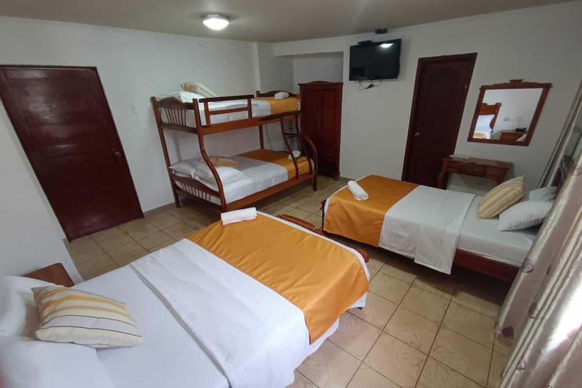 A room with two single beds, a bunk bed, a television, and a mirror.
