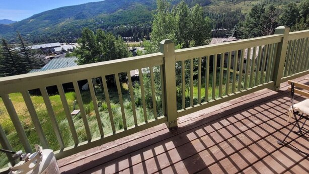Una terraza de madera con barandilla que da a un paisaje montañoso.