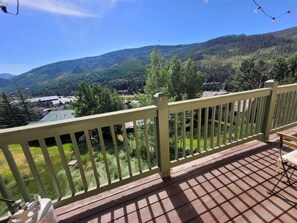 Une terrasse en bois avec une balustrade donnant sur un paysage montagneux.