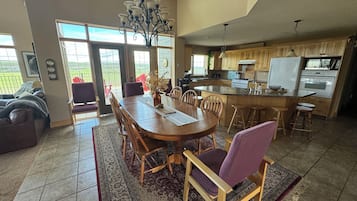 A spacious dining area with a large wooden table, surrounded by chairs, and a chandelier.
