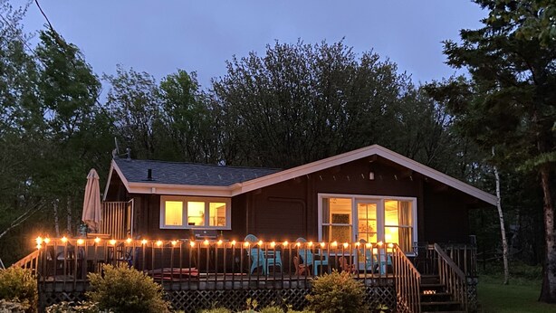 En stuga med en terrass, en inglasad veranda och en trappa som leder upp till entrén.
