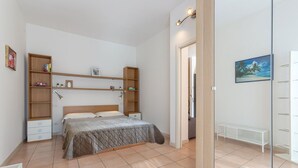 A bedroom with a bed, built-in shelving, a bedside table, and a mirror. - GuestHost - Porta Maggiore Apartment (Bologna)