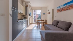 A compact living space with a kitchenette, dining area, and a sofa. - GuestHost - Porta Maggiore Apartment (Bologna)