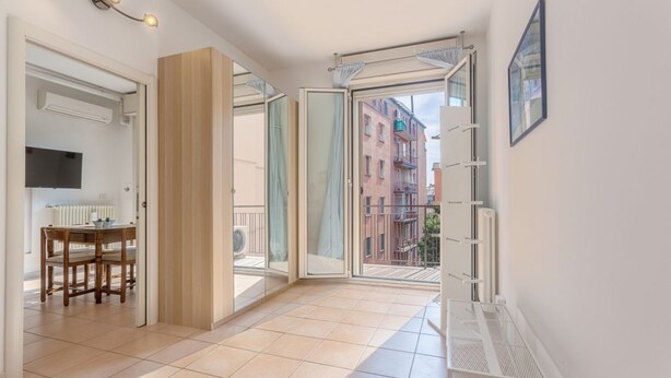 A spacious room with a balcony, a dining area, and a view of buildings. - GuestHost - Porta Maggiore Apartment (Bologna)