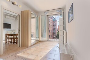 Un'ampia stanza con un balcone, un'area pranzo e vista sugli edifici.