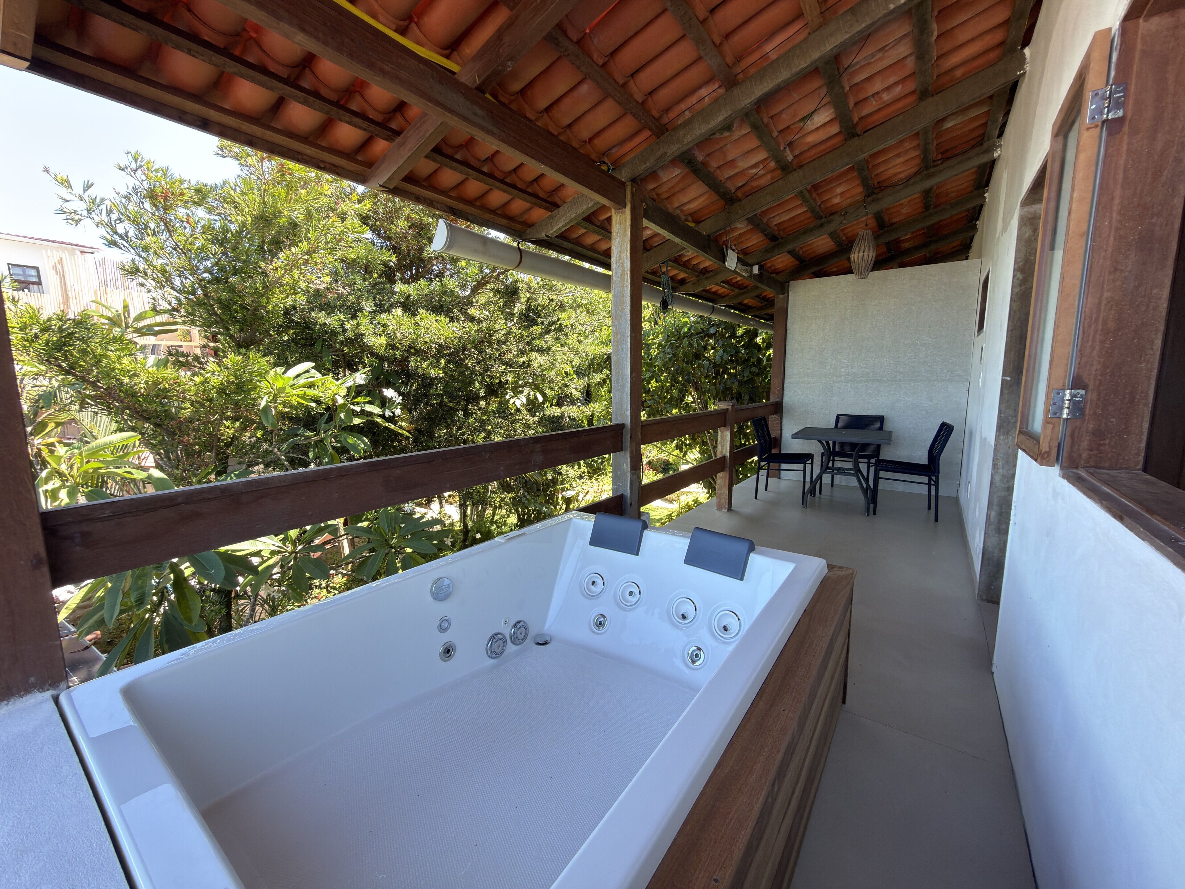 Un espace bien-être comprenant une grande baignoire, une terrasse en bois et un coin salon extérieur.