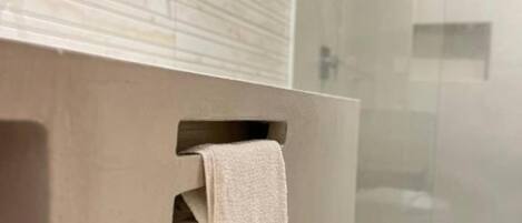 A modern bathroom with a glass shower enclosure, a beige vanity, and a white towel hanging on the towel rack.