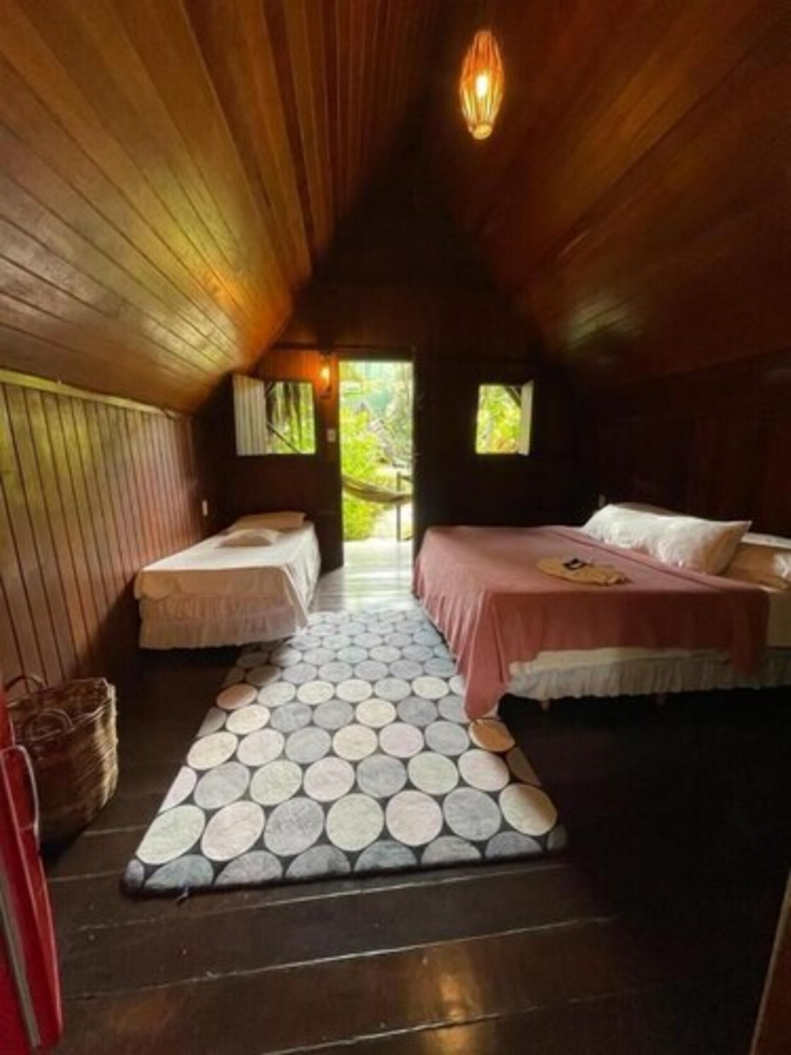Una habitación acogedora con dos camas, un tapete estampado y techo de madera.