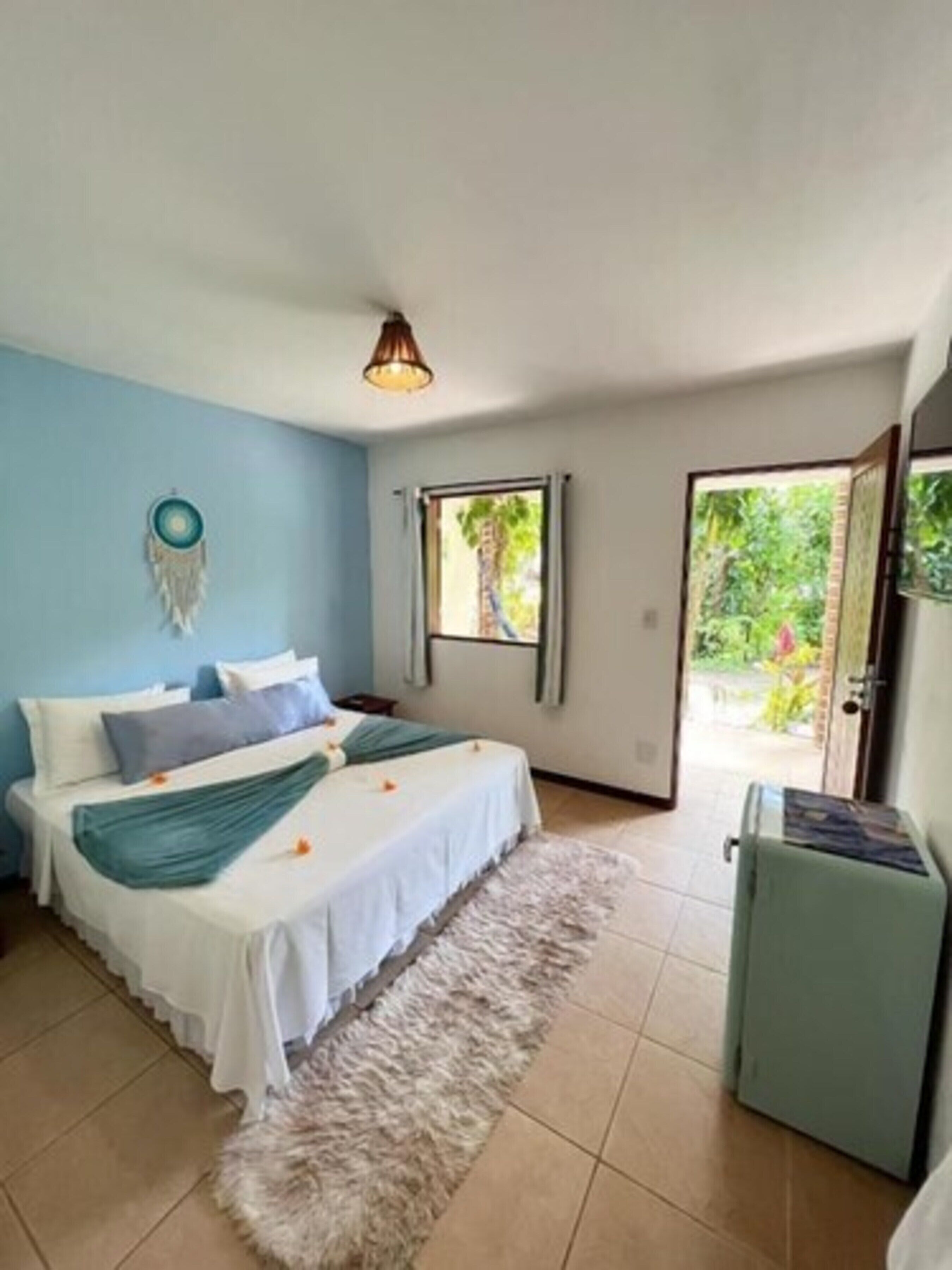 Un dormitorio con cama, una mesita, un calentador y una ventana con vistas a zonas verdes.
