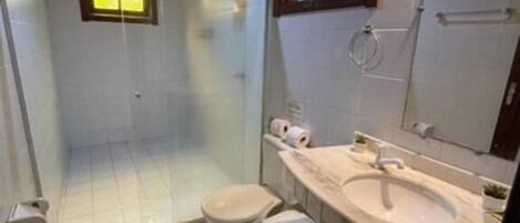 Ein Badezimmer mit einer Duschkabine, einer Toilette und einem Waschbecken mit Spiegel.
