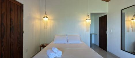 Un dormitorio con una cama grande, techo de madera, dos candelabros en la pared y un espejo amplio.