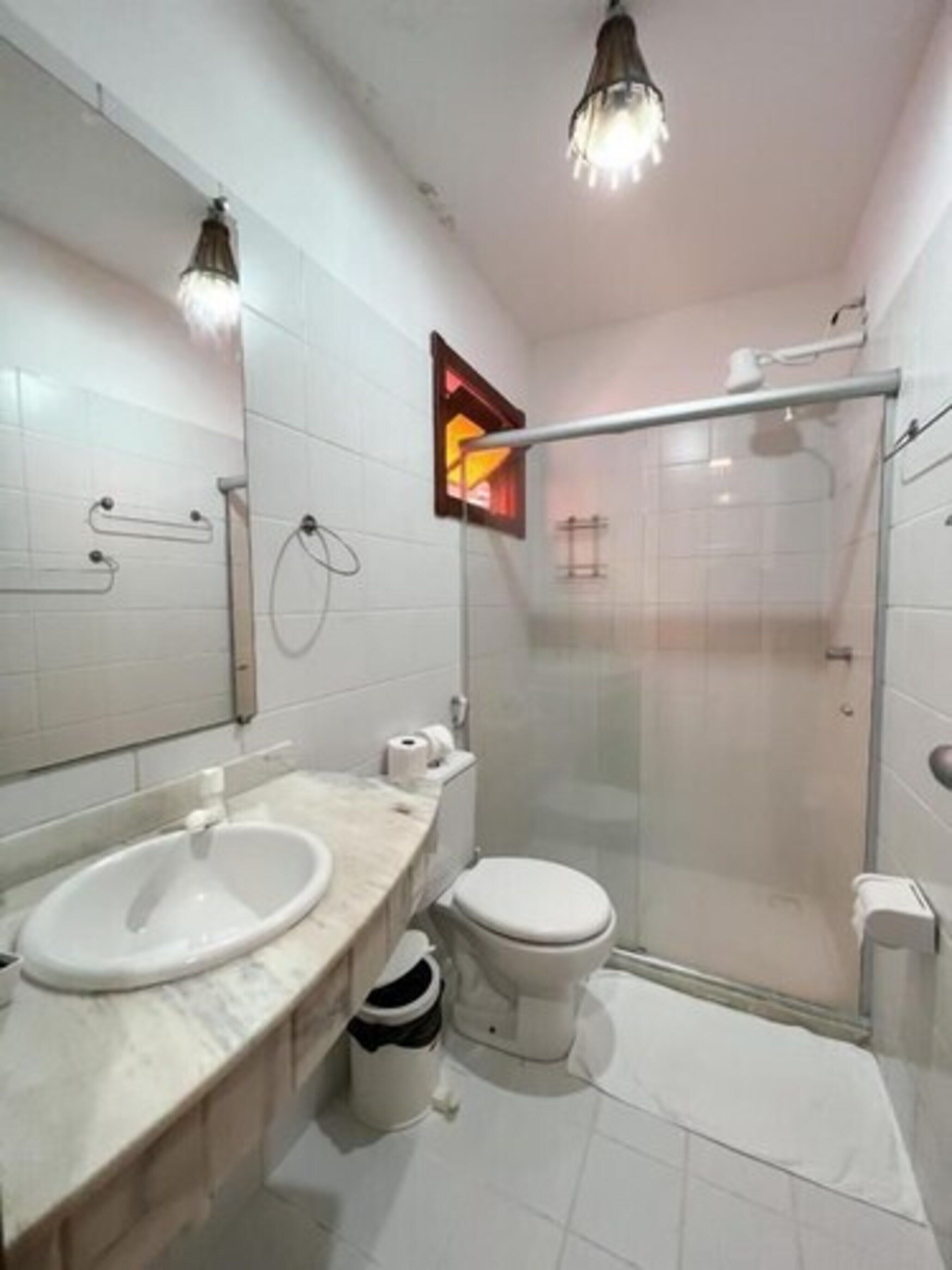 Un baño moderno con cabina de ducha de vidrio, un lavabo blanco y un inodoro.