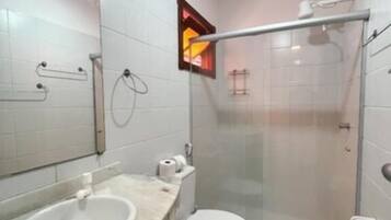 Un baño moderno con cabina de ducha de vidrio, un lavabo blanco y un inodoro.