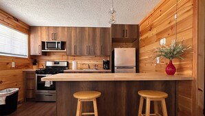 Una cocina moderna con armarios de madera, electrodomésticos de acero inoxidable y una isla central con taburetes.