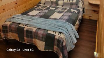 A cozy wooden cabin room with a bed, a window, and a view of the outdoors.