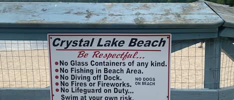 A sign at Crystal Lake Beach with rules like no glass containers, no fishing, and no dogs on the beach.