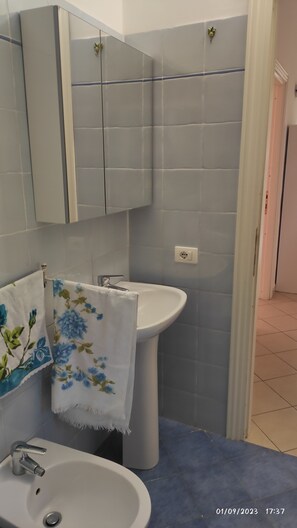 Ein Badezimmer mit Waschbecken, Spiegel und Fliesen.