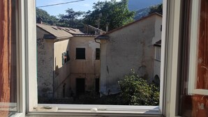 A window with a view of a courtyard with buildings, a radiator, and a green object in the foreground. - 2.5 km from the sea of Levanto, on the first hill, in a green and quiet location (levanto)