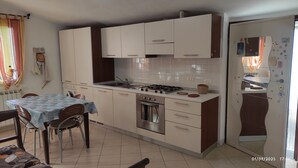 A modern kitchen with white cabinets, a gas stove, a built-in oven, and a dining area with a table and chairs. - 2.5 km from the sea of Levanto, on the first hill, in a green and quiet location (levanto)