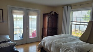 A bedroom with a bed, a dresser, a window with blinds, and a view of a dock and boats. - Pinnacle of St. Andrews by the Sea - Exquisite seaside home. (St. Andrews)