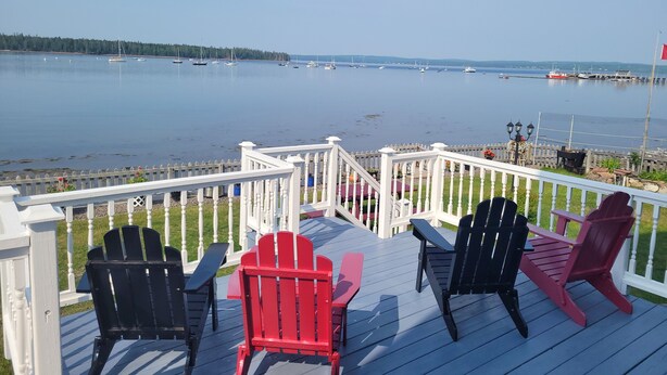 A deck with Adirondack chairs overlooking a calm lake with boats. - Pinnacle of St. Andrews by the Sea - Exquisite seaside home. (St. Andrews)