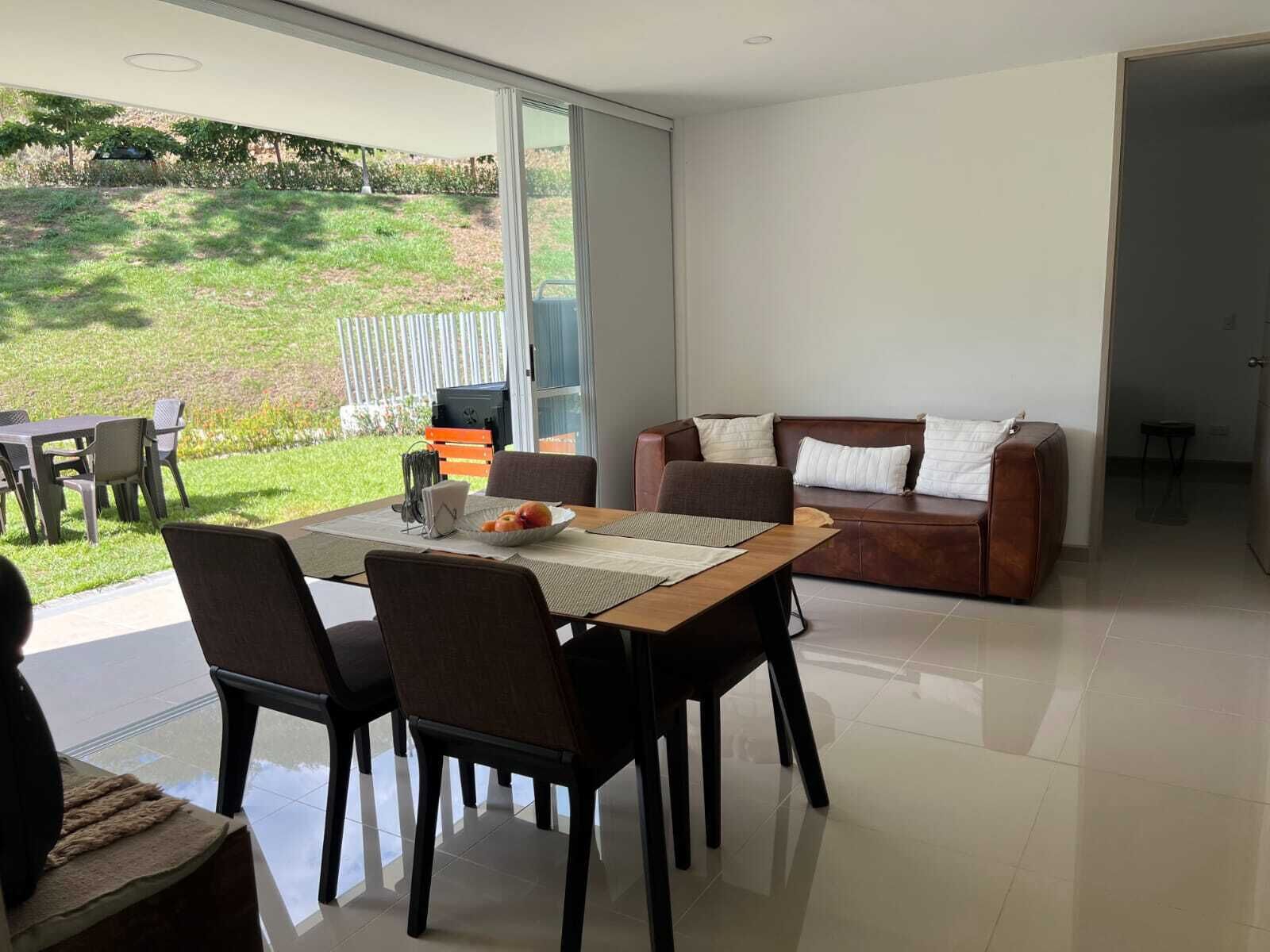 Uma sala de estar moderna com área de jantar, um sofá e vista para um jardim.