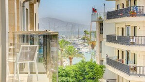 A balcony with a clear view of a marina and boats, a glass enclosure with a chair, and a building with balconies and railings. - Stunning 4 bed penthouse, direct acess to rooftop pool with 360o views of Port (Pollença)