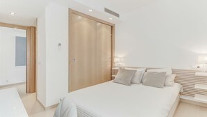 A modern bedroom with a large bed, bedside tables, and a wardrobe. - Stunning 4 bed penthouse, direct acess to rooftop pool with 360o views of Port (Pollença)