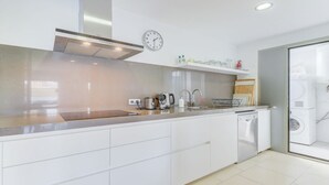 A modern kitchen with white cabinetry, stainless steel appliances, a built-in oven, and a dishwasher. - Stunning 4 bed penthouse, direct acess to rooftop pool with 360o views of Port (Pollença)