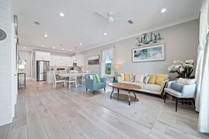 A spacious living area with a dining table, sofas, and a kitchen in the background.