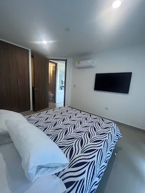 A bedroom with a bed, a wardrobe, an air conditioner, and a television on the wall. - Apartment In Bello Horizonte (Santa Marta)