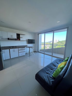 A modern kitchen with white cabinets, a flat-screen TV, and a dining area with a table and chairs. - Apartment In Bello Horizonte (Santa Marta)
