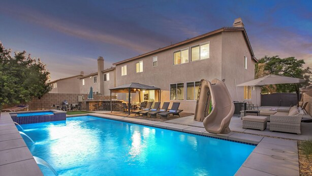 A swimming pool with lounge chairs and a covered patio area.