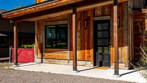 A modern wooden building with large windows and a red door. - Impressive, brand new modern residence in Whitefish. Close to downtown, lake and ski bus! (Whitefish)