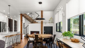 A modern kitchen with a wooden dining table, black chairs, and a large window. - Impressive, brand new modern residence in Whitefish. Close to downtown, lake and ski bus! (Whitefish)