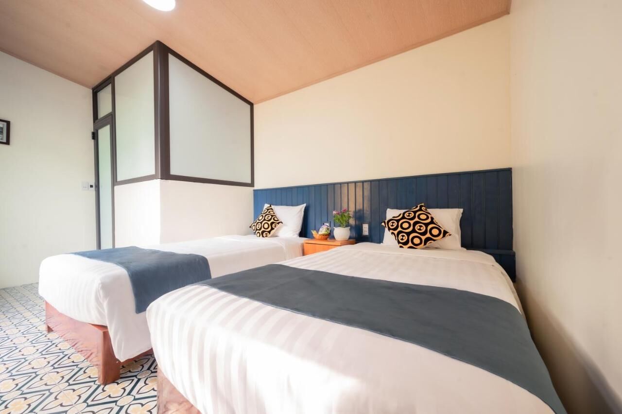 Habitación de hotel con dos camas, un espejo grande y piso estampado.