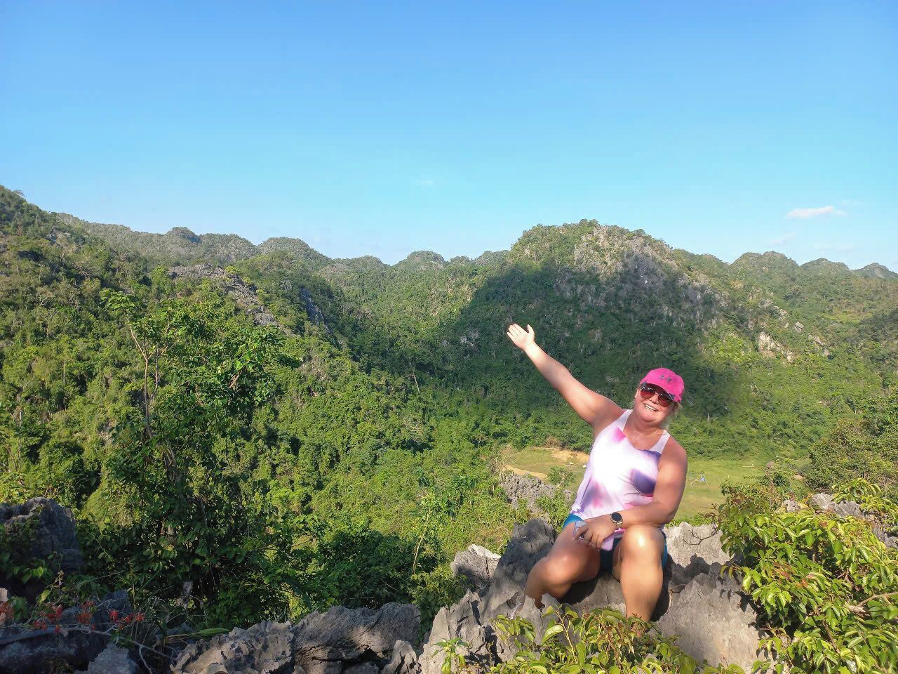 A person sitting on a rock with a mountainous landscape in the background.