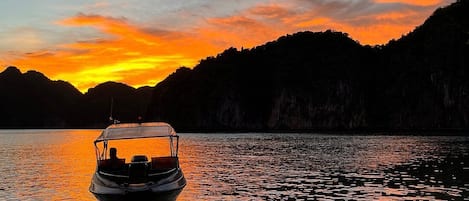 Un bote sobre aguas tranquilas con un atardecer de fondo.