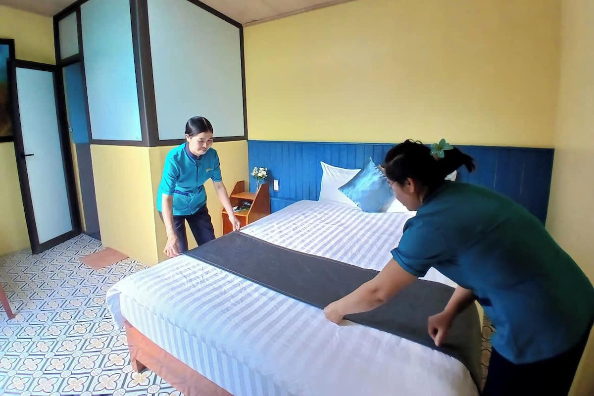 Una habitación de hotel con una cama, una mesita de noche y una pared azul.