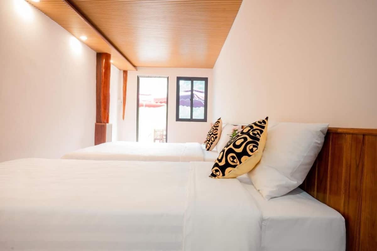 Habitación de hotel con dos camas y cabeceros de madera, bajo un techo inclinado.