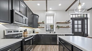 Une cuisine moderne avec des meubles de couleur sombre, un plan de travail blanc et un grand îlot central.