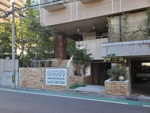 A youth hostel with a signboard, a gated entrance, and a parking area. - Youth Hostel Sonomama (Kofu)