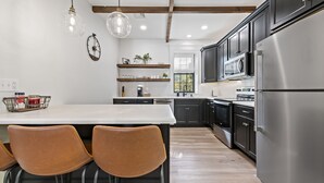 A modern kitchen with a central island, stainless steel appliances, and wooden beams.