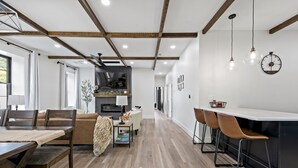 A modern kitchen with a central island, wooden flooring, and pendant lighting.