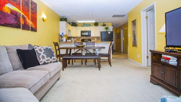 A living room with a sofa, a dining table, and a TV stand.