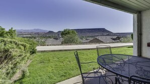Eine Terrasse mit Tisch und Stühlen mit Blick auf eine hügelige Landschaft.